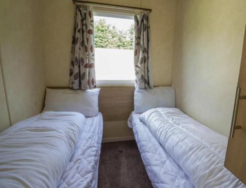 two beds in a small room with a window at Immaculate 3-Bed Caravan with Hot Tub in Lincoln