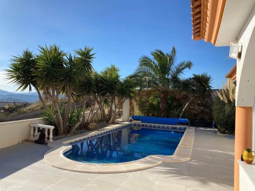 a swimming pool in a yard with palm trees at Veronica Villa in Partaloa