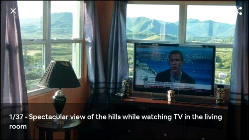 a flat screen tv sitting in a room with windows at Zeus Estate Guesthouse in Grays Hill