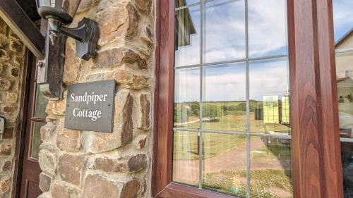 a sign on the side of a building with a window at Sandpiper Cottage: cosy home near the beach in Woolacombe