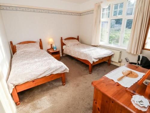 a bedroom with two beds and a table and a window at Goodrest in Verwood