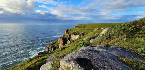 a grassy hill next to the ocean with rocks at Ankervas in Morganʼs Bay