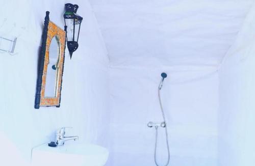 ein Bad mit einem Waschbecken und einem Wandspiegel in der Unterkunft Desert Berber Fire-Camp in Merzouga