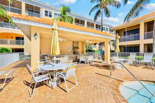 a patio with a table and chairs and a building at Amazing & Spacious Top Floor Condo with Bay View! in Marco Island