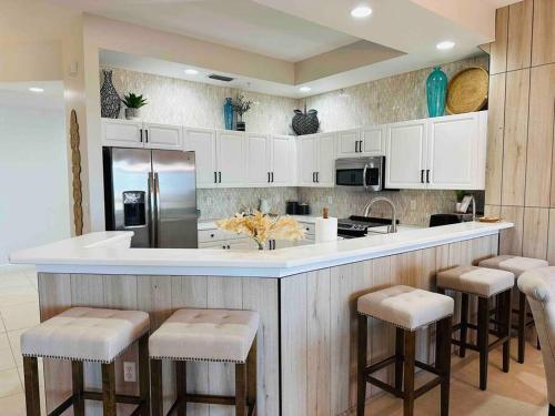 a kitchen with white cabinets and a counter with stools at Amazing & Spacious Top Floor Condo with Bay View! in Marco Island