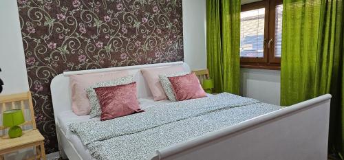 a bedroom with a bed with pink pillows and green curtains at AG Euro Apartments in Gabčíkovo