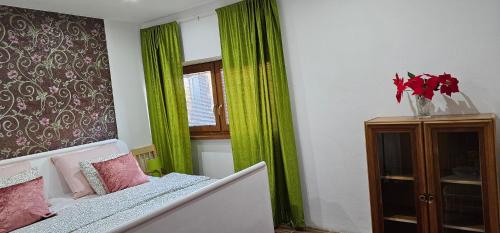 um quarto com cortinas verdes, uma cama e uma janela em AG Euro Apartments em Gabčíkovo