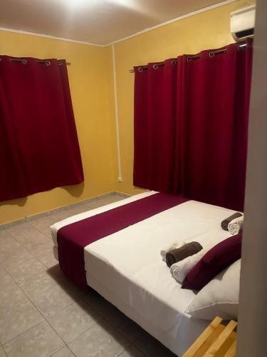 - une chambre avec un lit et des rideaux rouges dans l'établissement Chez Thythy, à Bouéni