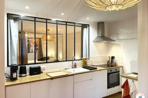 une cuisine avec des placards blancs et une grande fenêtre dans l'établissement Le Terracotta - Standing - Lumineux, à Rouen