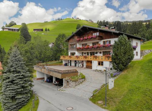 a large house with a balcony on a hill at Gästehaus Almhof in Zöblen