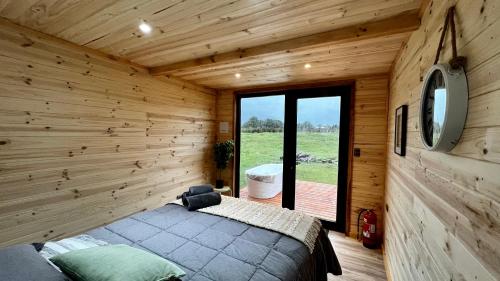 1 dormitorio con 1 cama en una habitación de madera en Puerta austral, en Puelo