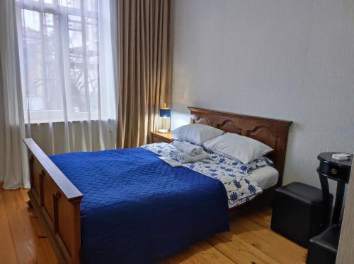 a bedroom with a bed with a blue blanket and a window at Friendly Guest House in Kutaisi