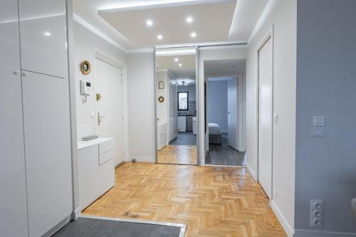 um corredor com paredes brancas, pisos de madeira e um espelho em Place du Général Leclerc à Saint-Mandé PARIS - 3P em Saint-Mandé