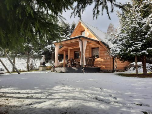 a log cabin in the snow with a yard at Domki z jacuzzi Pasja I in Mizerna