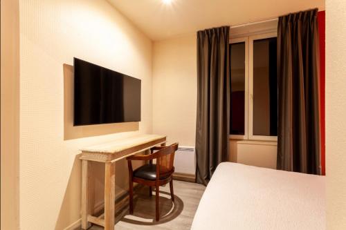 a hotel room with a desk and a television at Providence Hotel in Vittel