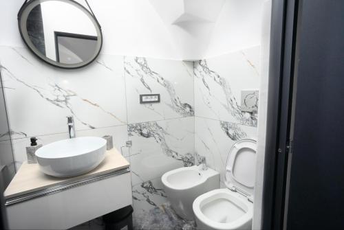 Un baño con lavabo, inodoro y espejo. en Balcescu Residence, en Brasov