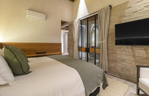 サンミゲル・デ・アジェンデにあるCasas y Suites Indigo San Miguelの大きなベッドと薄型テレビのある寝室