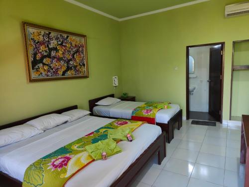 duas camas num quarto com paredes verdes em Berlian Inn Kuta Beach em Kuta