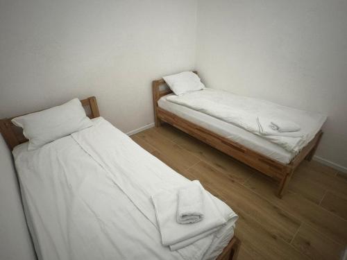 two beds in a small room with white sheets at Apartmani Andjela in Jahorina