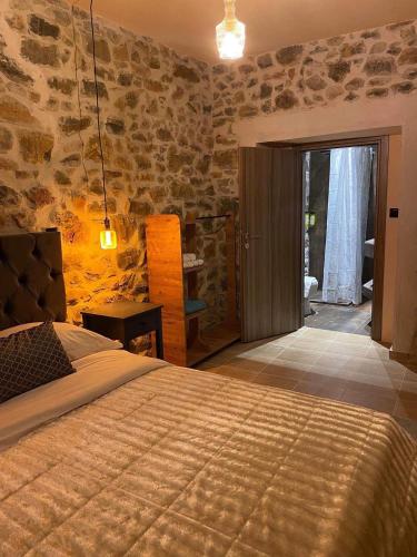 una camera con un letto in una stanza con pareti in pietra di Adeste to Lasithi Luxury Apartment a Mésa Lasithákion