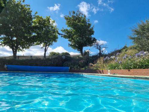einen Pool mit blauem Wasser und Bäumen in der Unterkunft Sandpiper Cottage: cosy home near the beach in Woolacombe