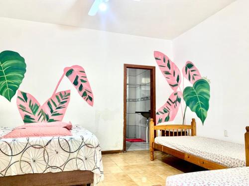 a bedroom with two beds and palm leaves on the wall at Floripa Camping e Hostel Florianopolis SC in Florianópolis