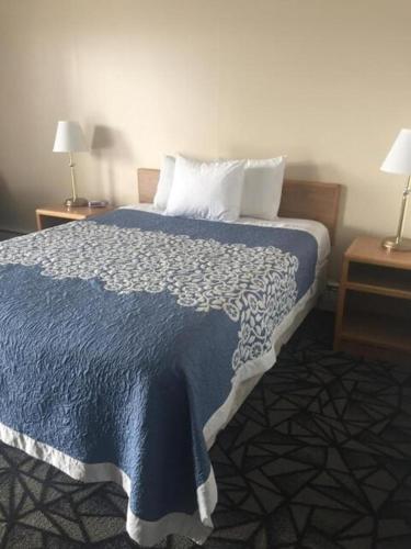 a bedroom with a bed with a blue blanket and two tables at Tomahawk Motor Lodge in Riverton