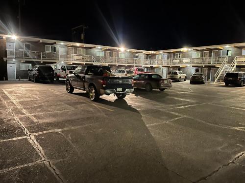 a parking lot with cars parked in front of a building at Tomahawk Motor Lodge in Riverton