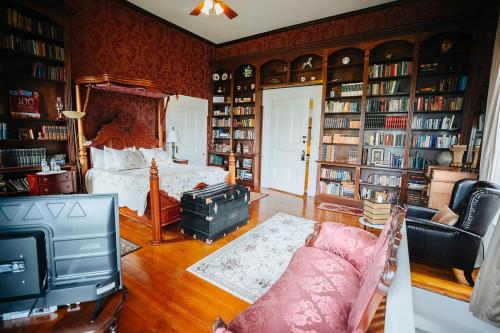 1 dormitorio con 1 cama, TV y estanterías de libros en Maple Hill Manor Bed & Breakfast, en Springfield