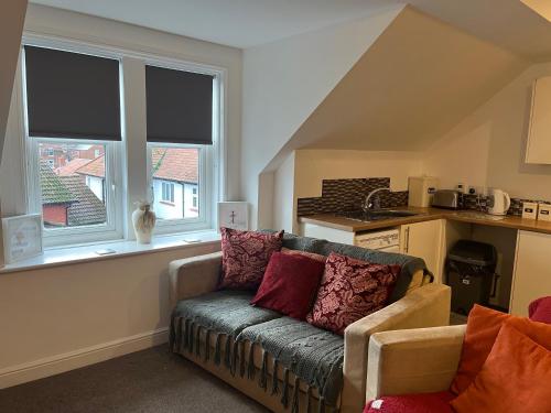 a living room with a couch and two windows at Apartment 8 at 19 Brooklands in Filey