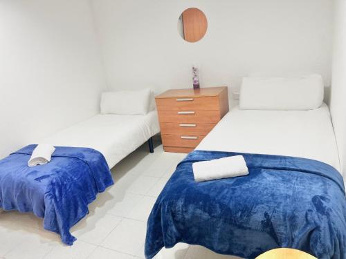 Habitación con 2 camas y tocador de madera. en Acogedor Apartamento, en Hospitalet de Llobregat