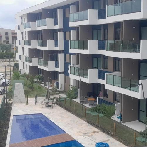 an apartment building with a swimming pool in front of it at Muro alto - porto de galinhas -Makia beach in Ipojuca