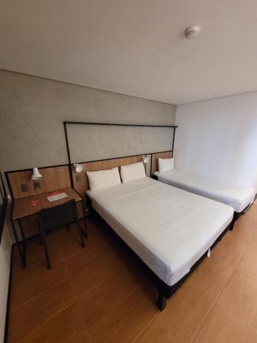 a bedroom with two beds and a night stand with a bed sidx sidx at ibis Maceio Pajuçara in Maceió