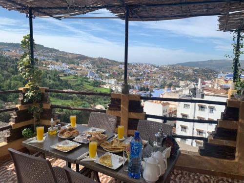 einen Tisch mit Speisen und Getränken auf einem Balkon mit Aussicht in der Unterkunft dream house sebanine in Chefchaouen