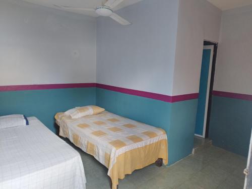 2 camas en una habitación con paredes azules y blancas en Hostal y Temazcal Guemez en Pisté