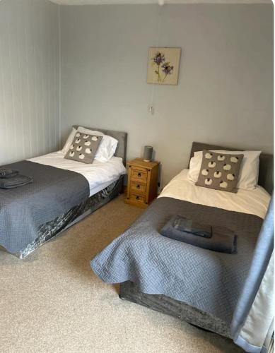 a bedroom with two beds and a night stand at Onchan House, Beal in Knottingly