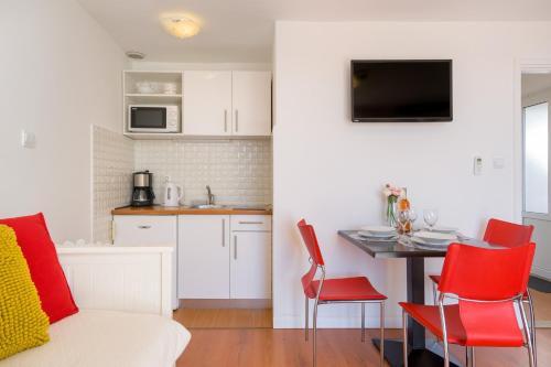 uma cozinha e uma sala de estar com uma mesa e cadeiras vermelhas em Apartment Cable car 1 em Dubrovnik