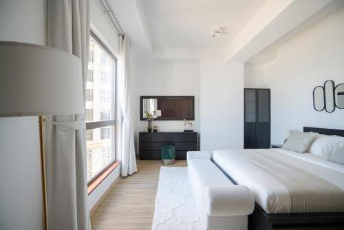 a white bedroom with a large bed and a window at GMA Amwaj 2BR Sea View High Floor in Dubai