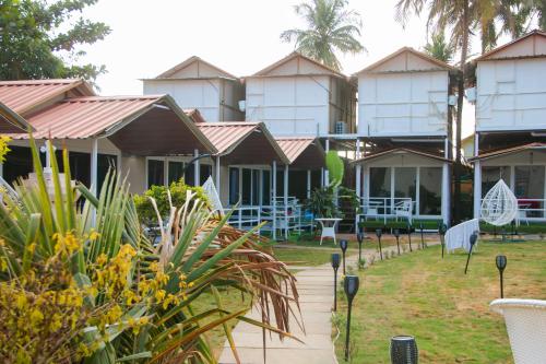 eine Reihe von Gebäuden mit Tischen und Stühlen in einem Garten in der Unterkunft Luxurious Beach Resort Agonda in Agonda