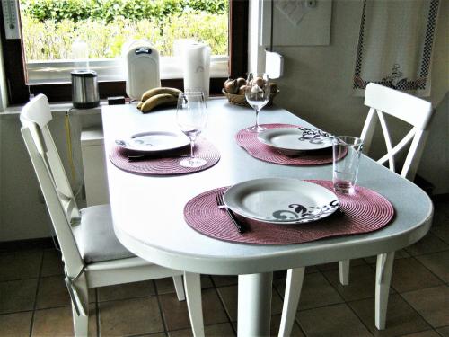 uma mesa de jantar branca com pratos e copos de vinho em FEWO Schlei-Hering bei Kappeln Ostsee em Oersberg