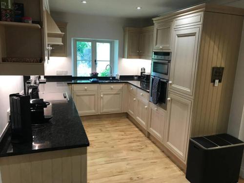 a kitchen with white cabinets and a black counter top at The Bolt Hole, Cotswold Cottage, Moreton-In-Marsh in Moreton in Marsh