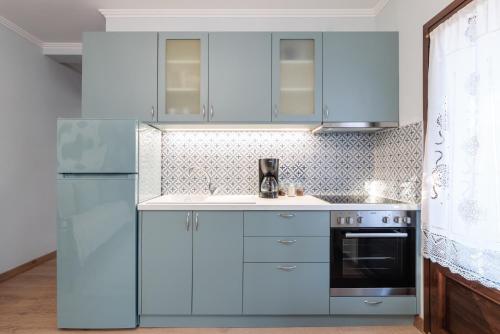 a kitchen with blue cabinets and a stove at Άρνη (η κόρη του Αιόλου) in Arnaia