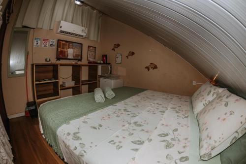 a bedroom with a bed with a green comforter at Doce Lar Hostel Noronha in Fernando de Noronha