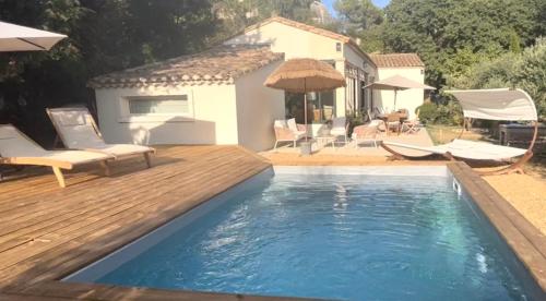 une piscine avec une terrasse en bois et une maison dans l'établissement maison aux Baux de Provence, aux Baux-de-Provence