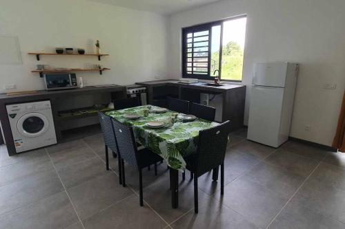 Il comprend une cuisine équipée d'une table, de chaises et d'un réfrigérateur. dans l'établissement Le Fare APE TARUA, à Taputapuapea
