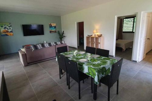 a dining room with a table with chairs and a couch at Le Fare APE TARUA in Taputapuapea