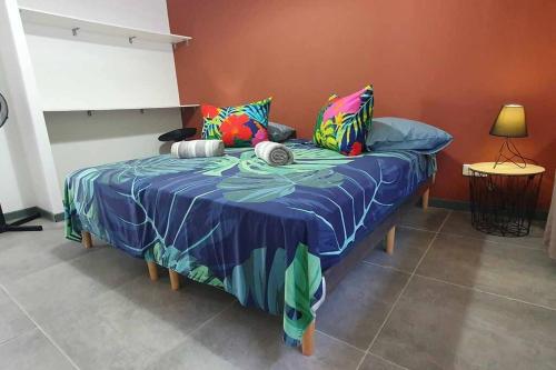 una cama con almohadas coloridas en una habitación en Le Fare APE TARUA, en Taputapuapea