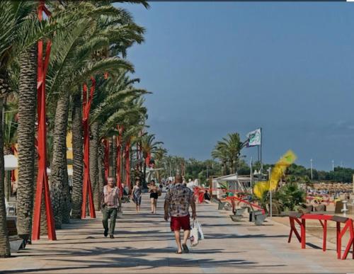 a group of people walking down a sidewalk with palm trees at Ca La Solé in Vinarós