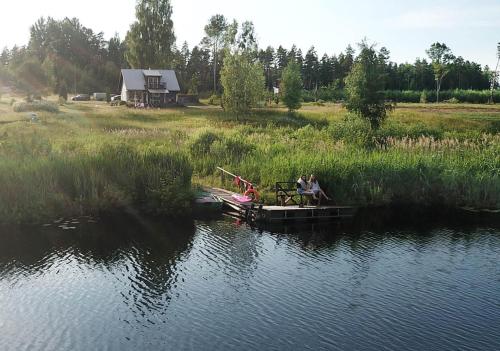 Meza Skuki في Vabole: يجلس شخصان على رصيف على بحيرة