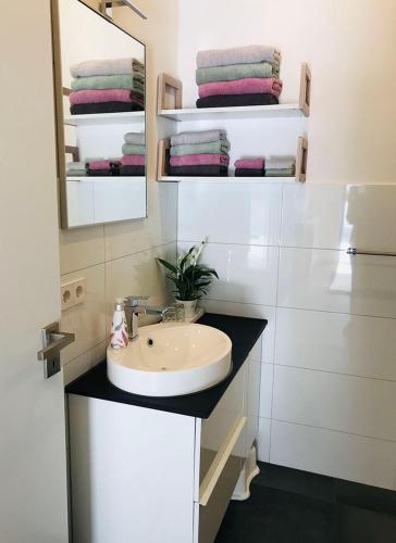 a bathroom with a sink and a mirror and towels at FERIENWOHNUNG SEEBRISE mit sonniger Dachterrasse in Uhldingen-Mühlhofen